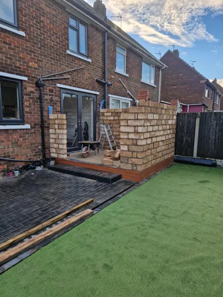 Rear extension brick walls going up beside artificial grass during brickwork