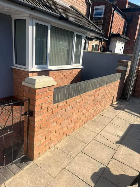 Red brick front wall with charcoal coping and stone capped pillar after completion
