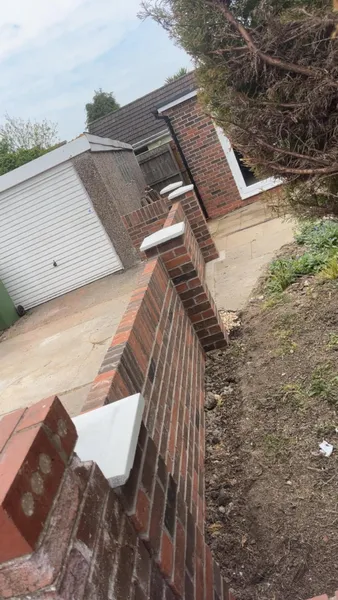Brick side garden wall being built towards a garage during brickwork