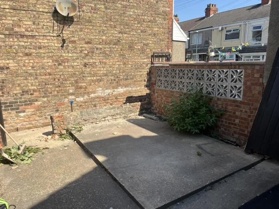 Old garden wall with decorative screen blocks and weeds before rebuild