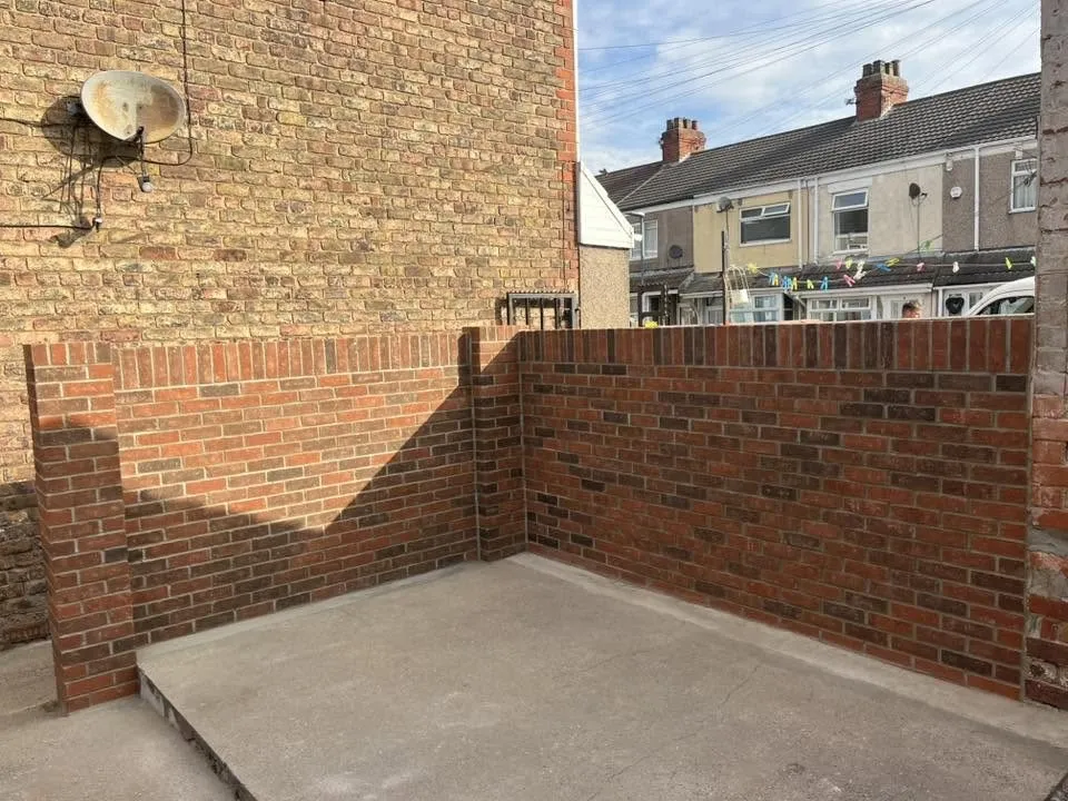 New red brick garden walls built round a concrete yard after rebuild