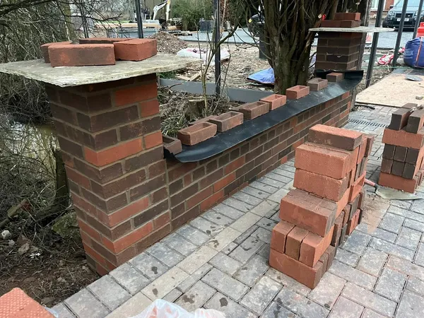 Brick gate pillars being built with coping stones during front wall work
