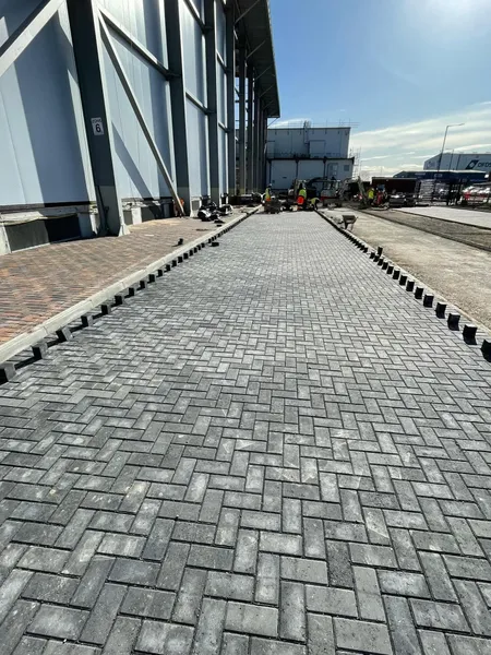 Charcoal commercial block paving laid beside a clad industrial building