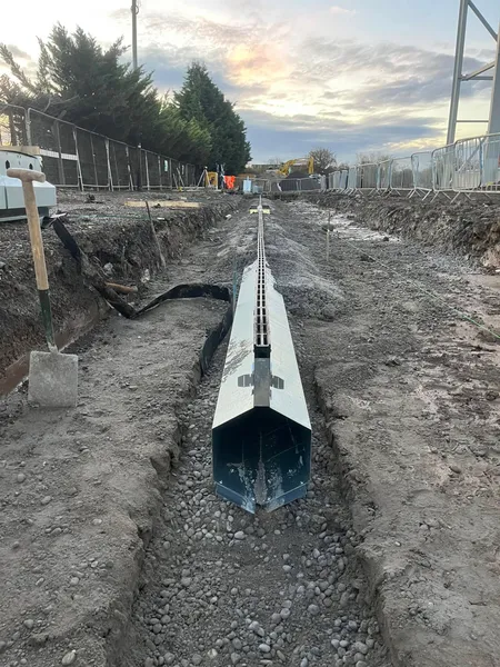 Steel slot drain channel laid on gravel bedding along a commercial trench