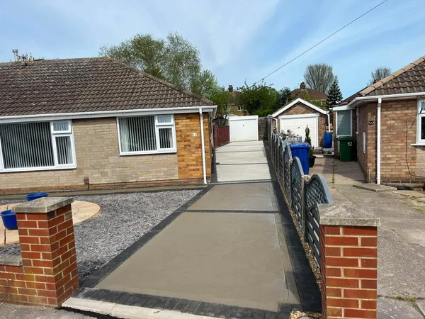 Concrete driveway with channel drain between brick pillars after completion