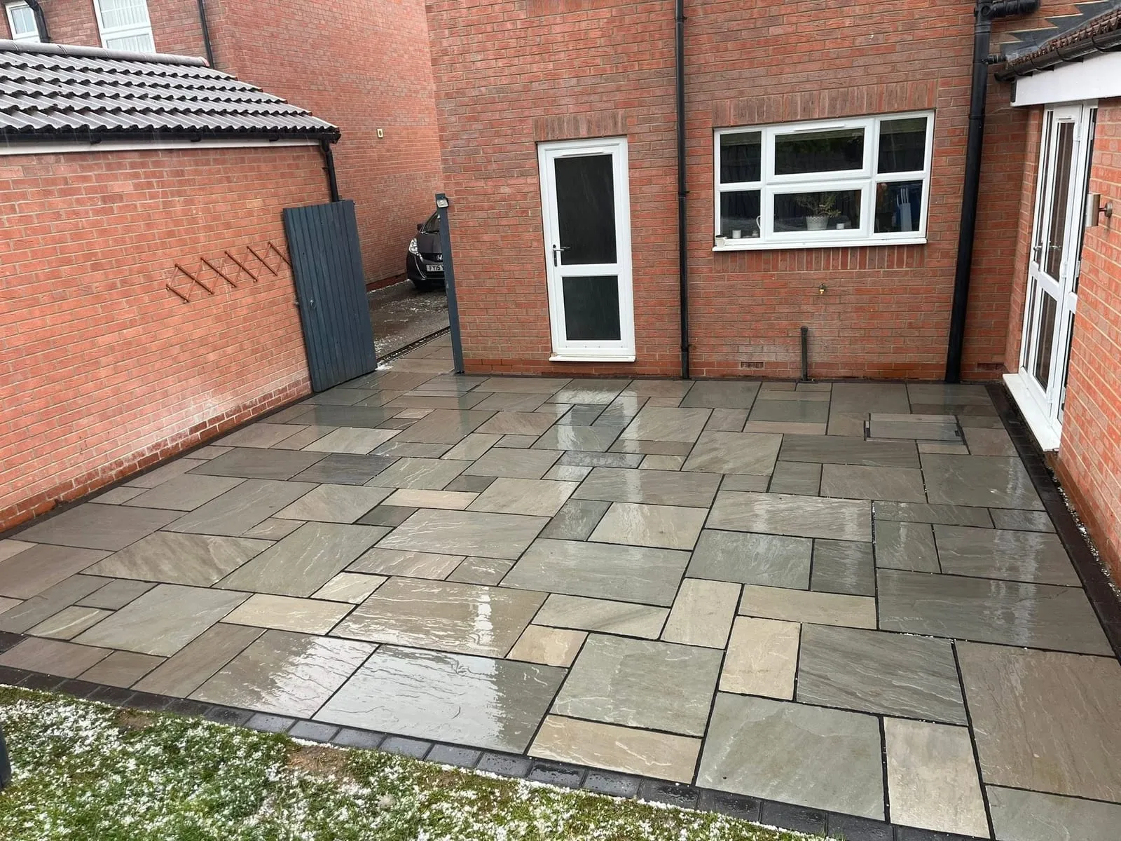 New grey and buff natural stone patio with a charcoal block border after completion