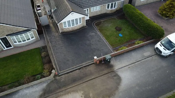 Aerial charcoal block paving drive with curved lawn edge after completion