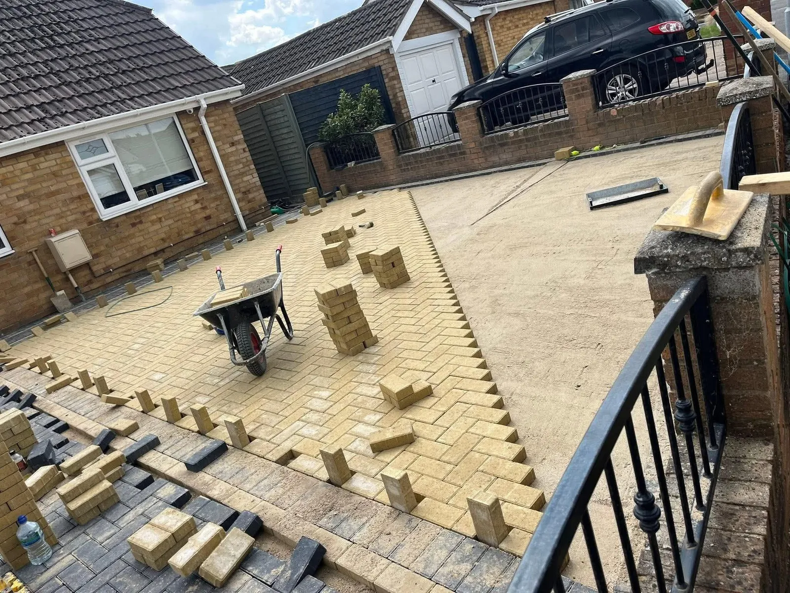Buff block paving being laid on a sand bed with a wheelbarrow during driveway work