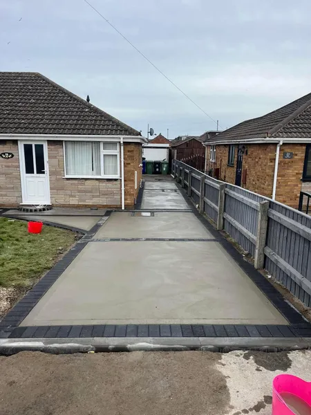 Long concrete drive with charcoal block border beside a bungalow after completion