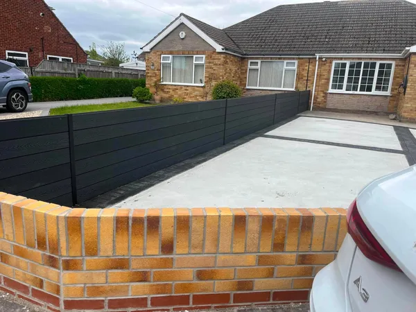 Concrete drive with charcoal block border behind a brick wall after completion