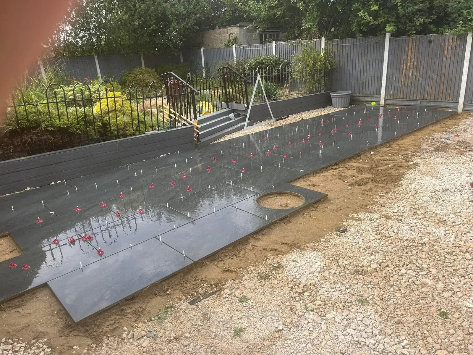 Dark grey porcelain patio slabs being laid with levelling clips during installation