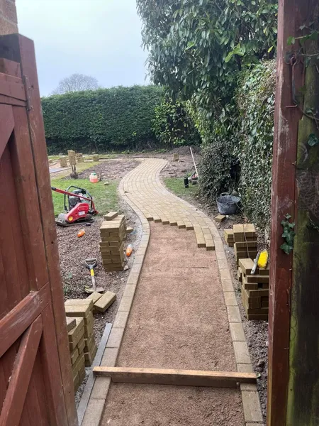 Curving garden path sub base with edging blocks stacked during path construction