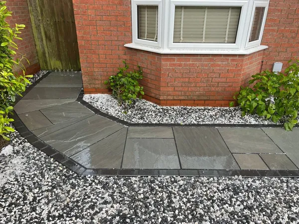 Curved grey slab path with charcoal block edge and white gravel border