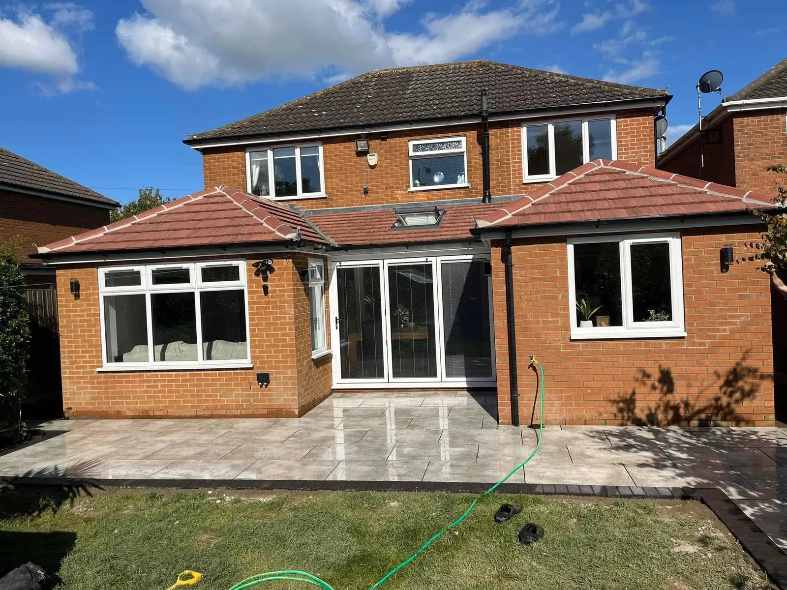 Grey porcelain patio finished at the rear of a red brick house after completion