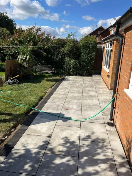 Grey porcelain patio running along a brick house wall after completion