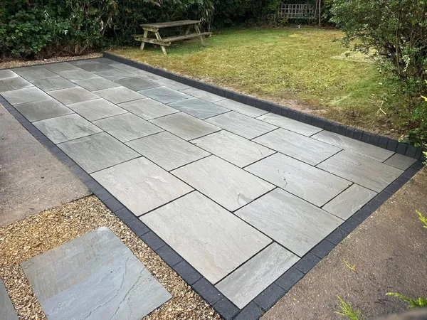 Grey slab patio with charcoal block edging and gravel after completion