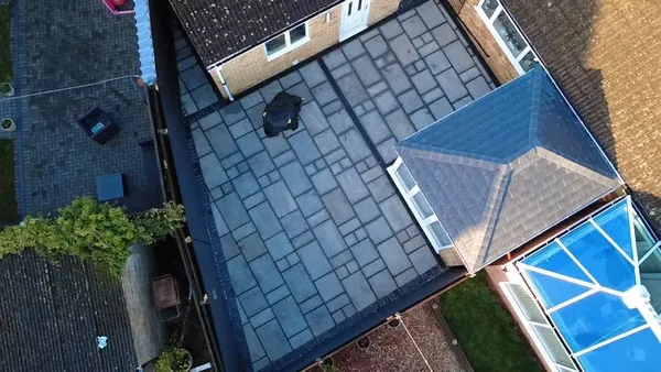Aerial grey slab patio with charcoal border beside a conservatory after completion