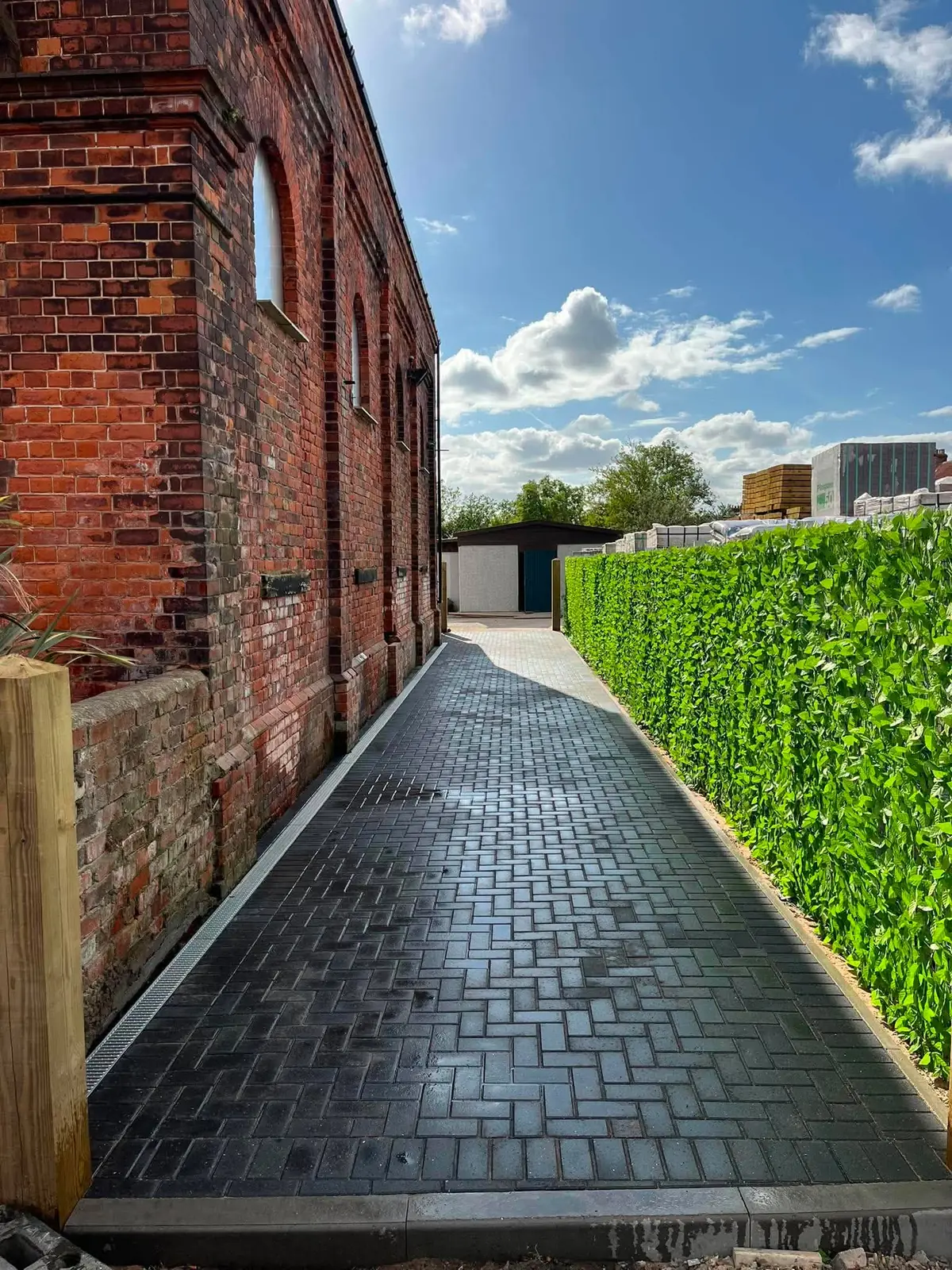 Charcoal block paving path along a chapel wall after completion