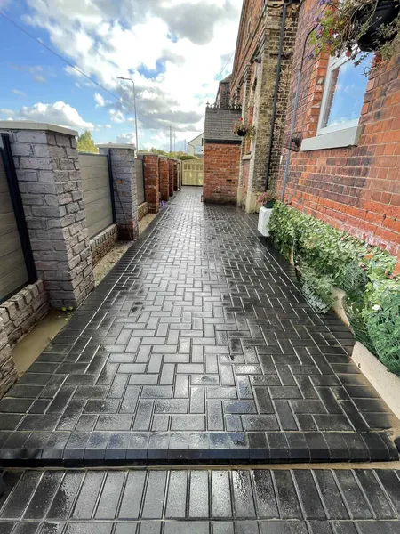 Charcoal block paving path between terraced houses and stone pillars after completion