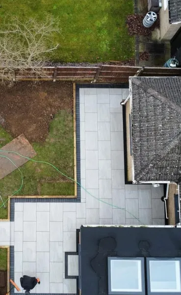 Aerial L shaped light porcelain patio round a bungalow after completion