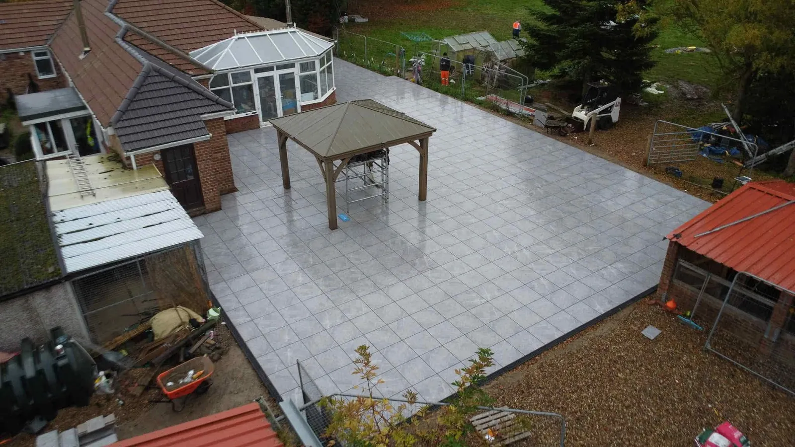 Aerial large grey porcelain patio with wooden gazebo after completion