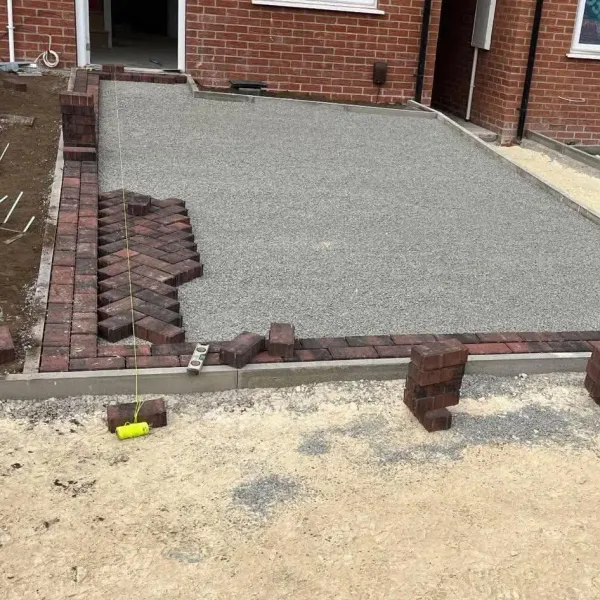 New build driveway being laid in brindle herringbone blocks inside a block border