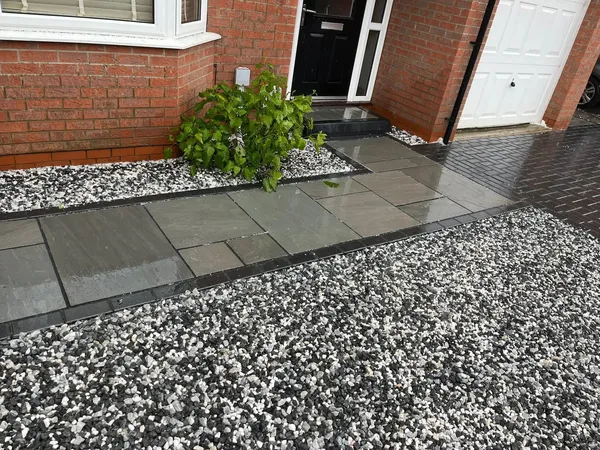 Grey slab front path with white decorative gravel border beside a house