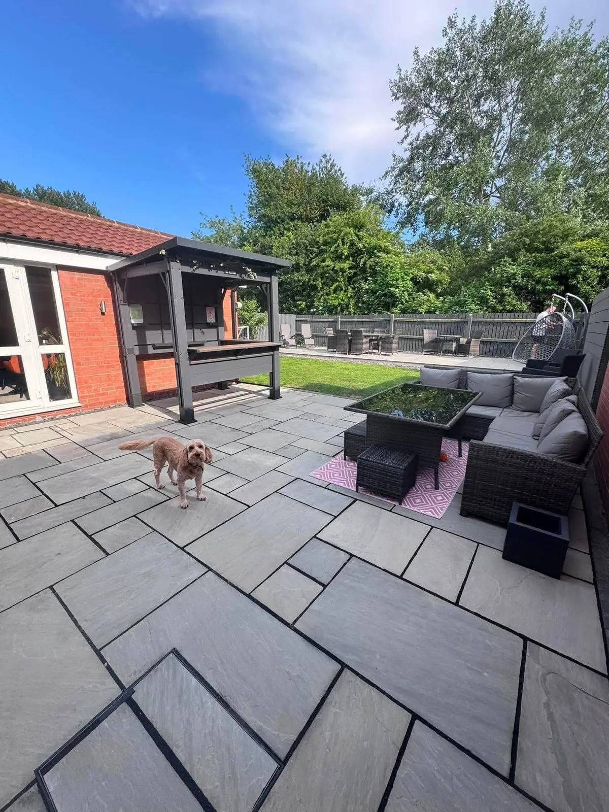 Grey slab patio laid in mixed size slabs beside a brick house after completion
