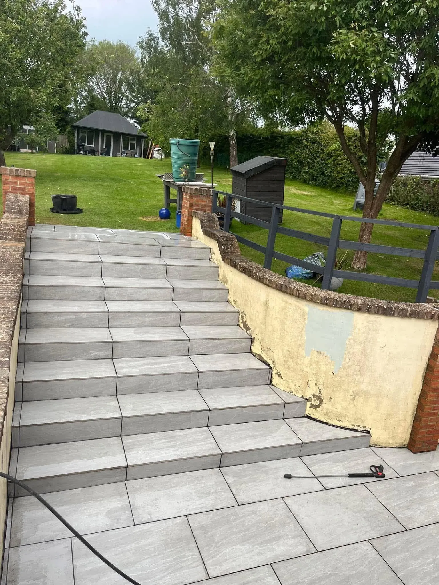 Grey porcelain garden steps rebuilt beside a rendered garden wall after completion