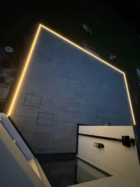 Dark porcelain patio with LED strip lighting along edges after completion at night