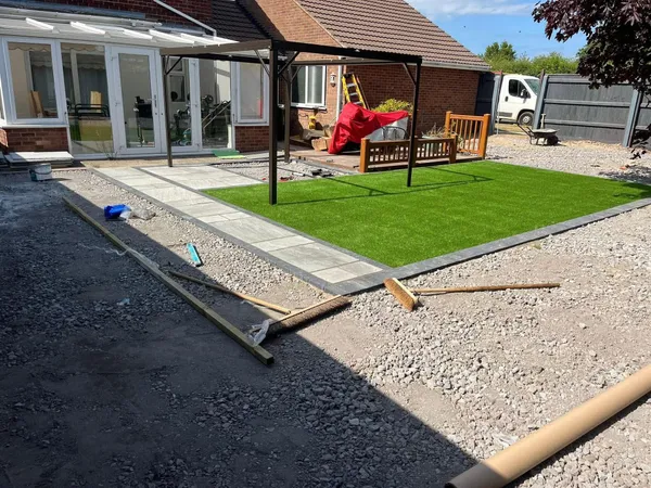 Artificial grass and slab path laid with pergola during garden preparation