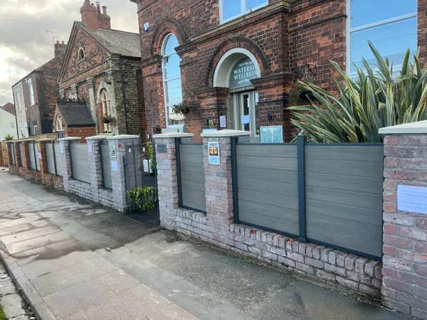 Grey composite fence panels between brick pillars along a front boundary after completion