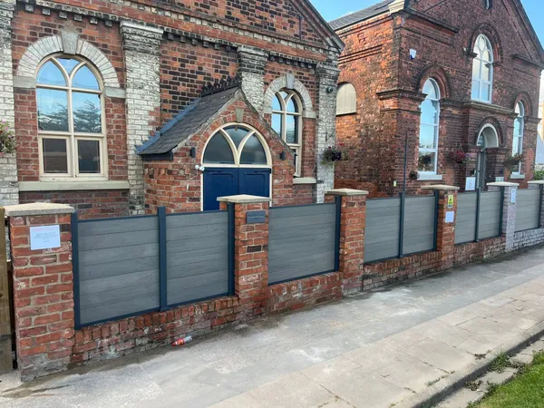 Grey composite fencing boards between red brick pillars beside a pavement after completion