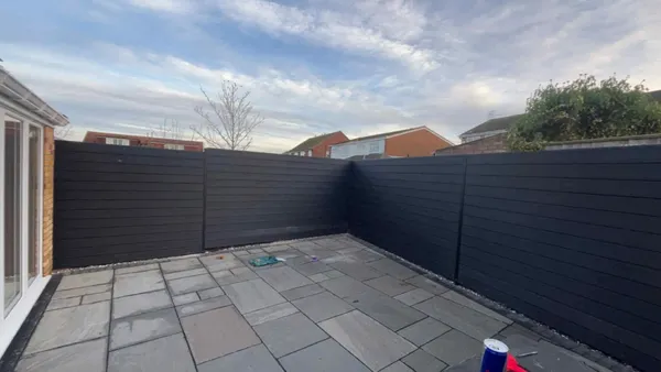 Composite fence and sandstone patio viewed from French doors after completion