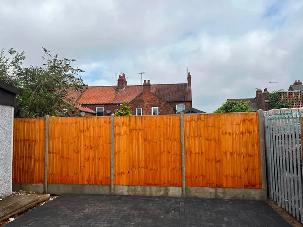 Featheredge wooden fence behind a charcoal block paved yard after completion