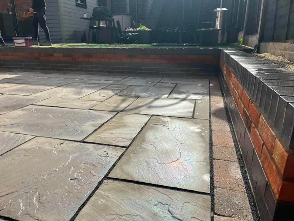 Indian sandstone patio with new red brick garden wall after completion