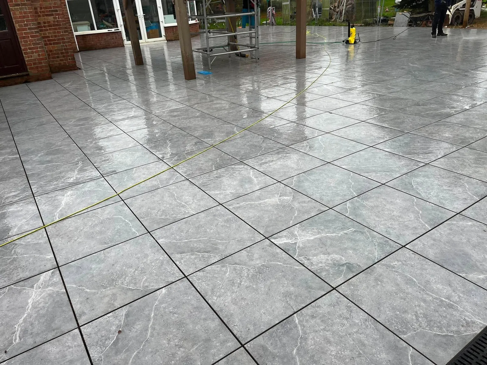 Large grey porcelain patio with channel drain set into paving after completion