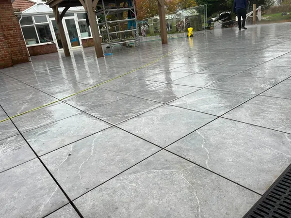 Grey porcelain patio channel drain detail after completion beside a house