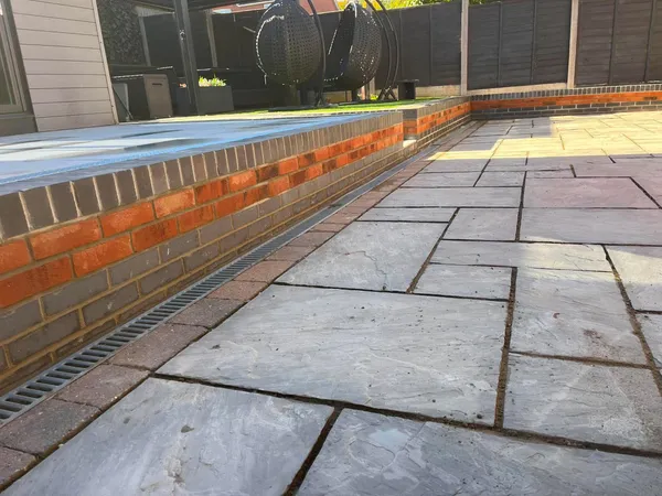 Sandstone patio channel drain beside a new brick garden wall after completion